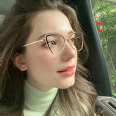 Woman wearing cat-eye glasses inside a vehicle with blurred background